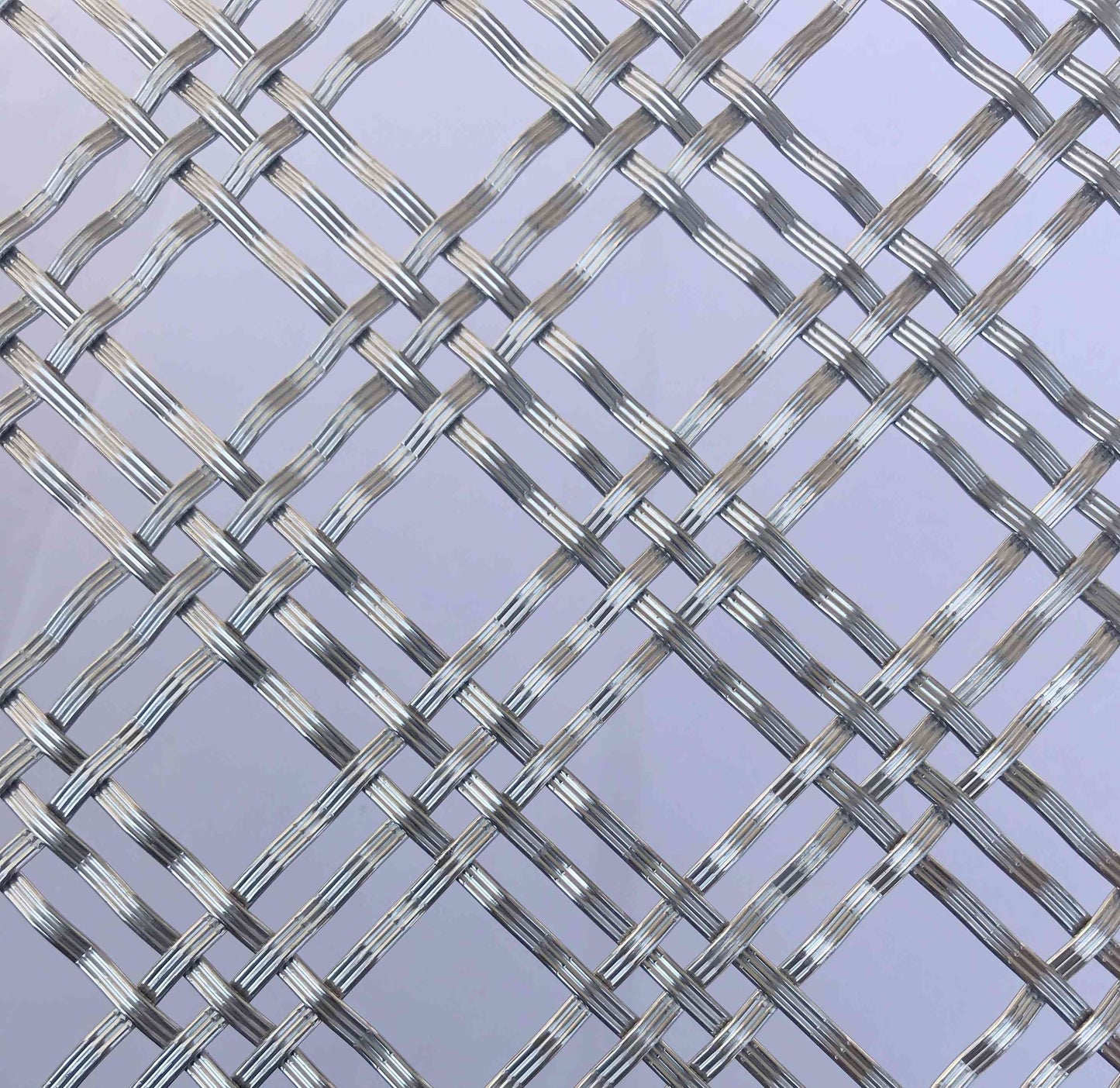 Metallic woven mesh on a light purple background