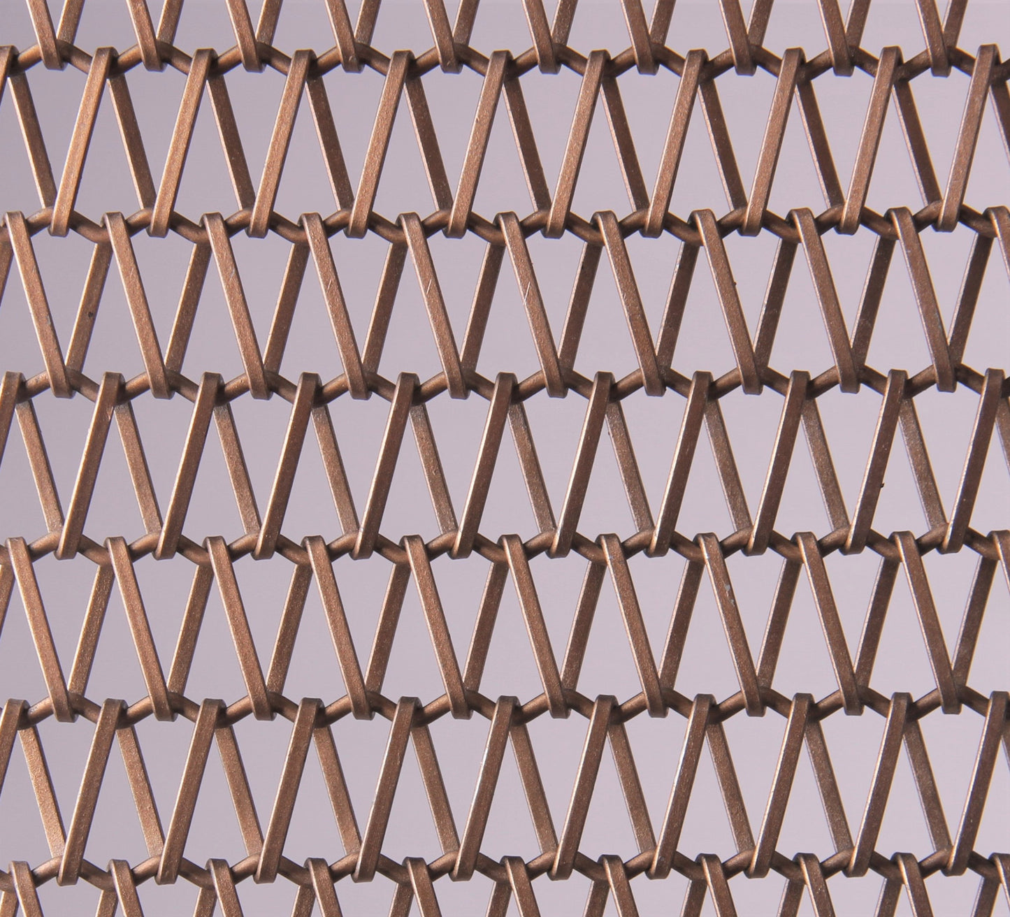 Close-up of a metal mesh with a geometric pattern on a gray background