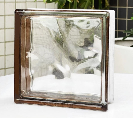 Clear glass block with a metallic frame on a white surface