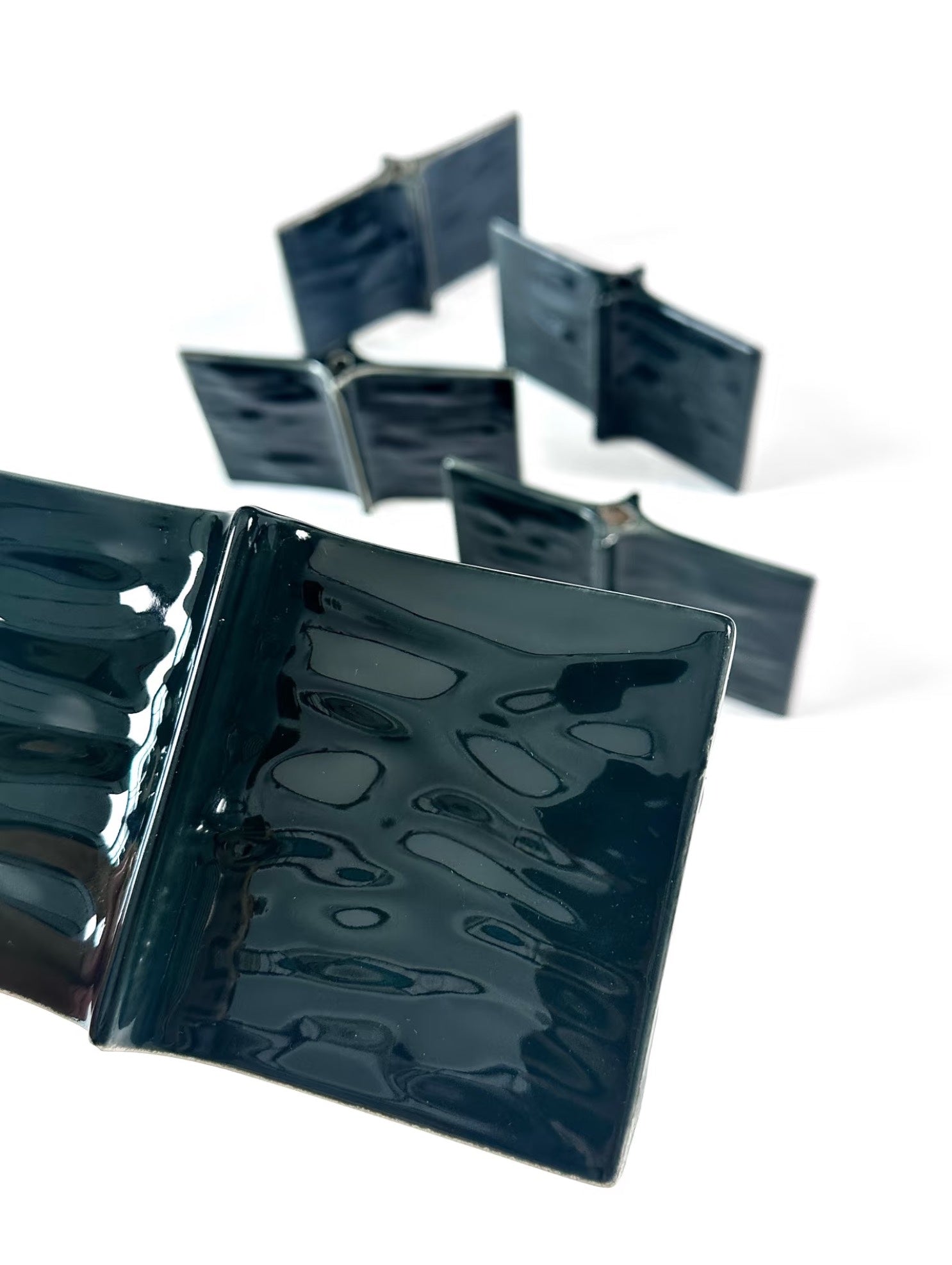 Set of black ceramic tiles with a glossy finish on a white background